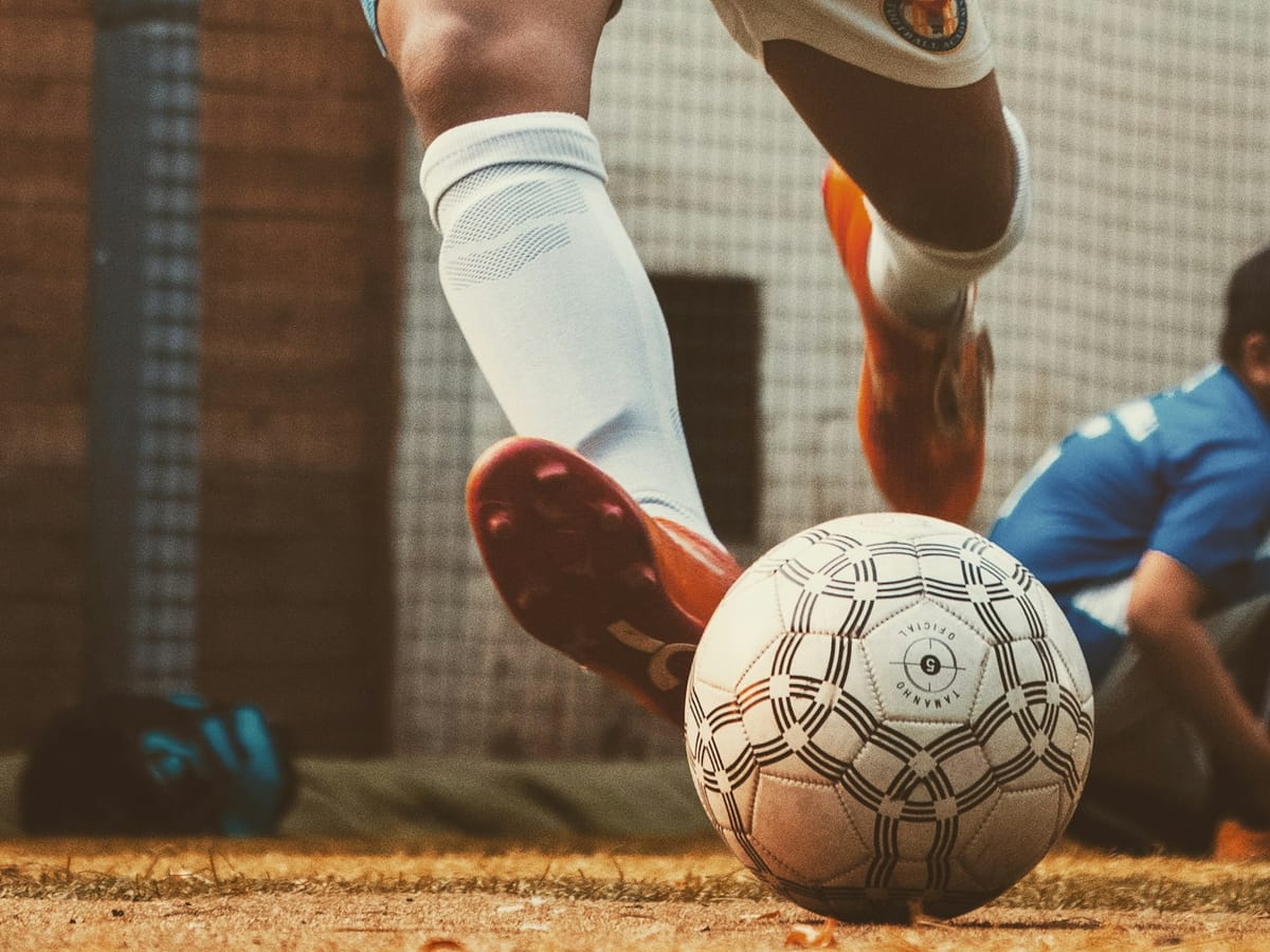 Calciatore che calcia un pallone su un campo da calcio