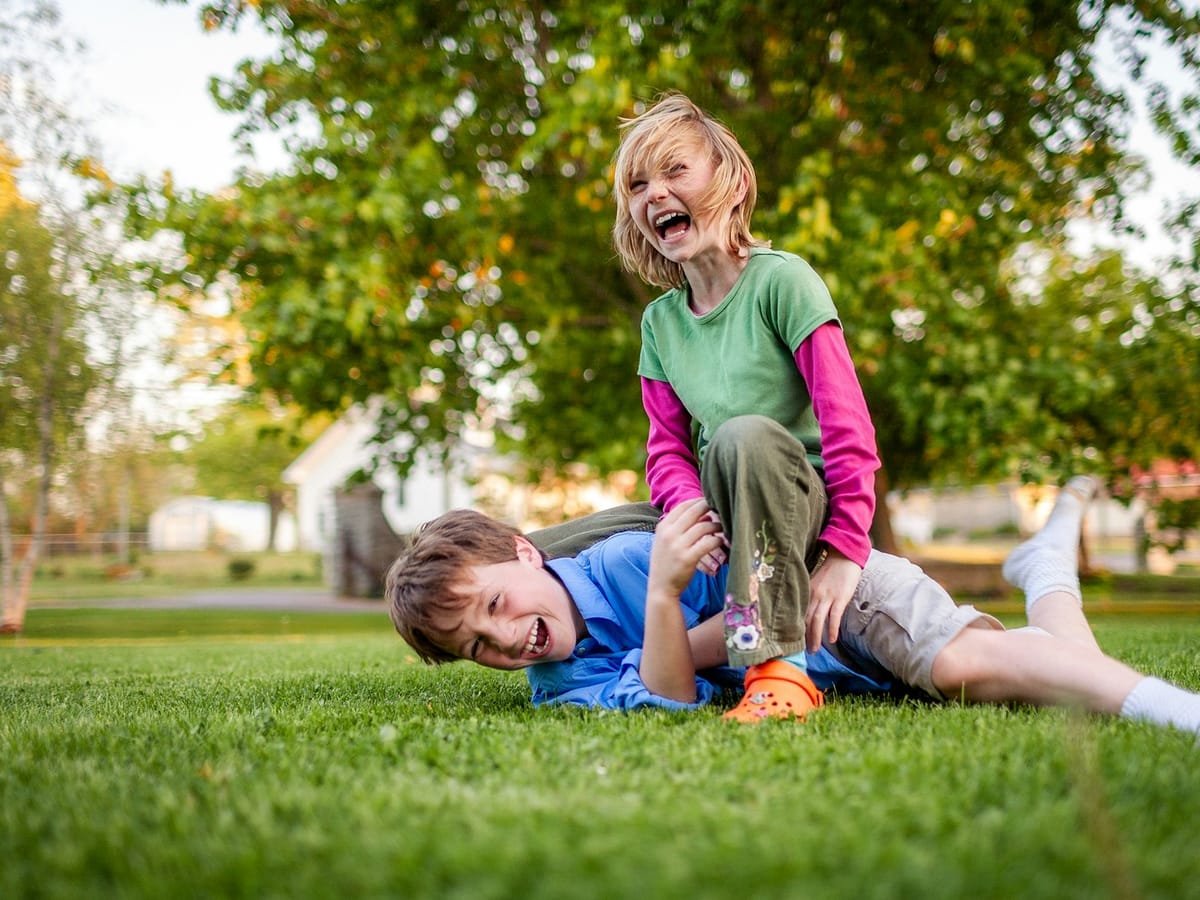 Due bambini che ridono e giocano sull'erba